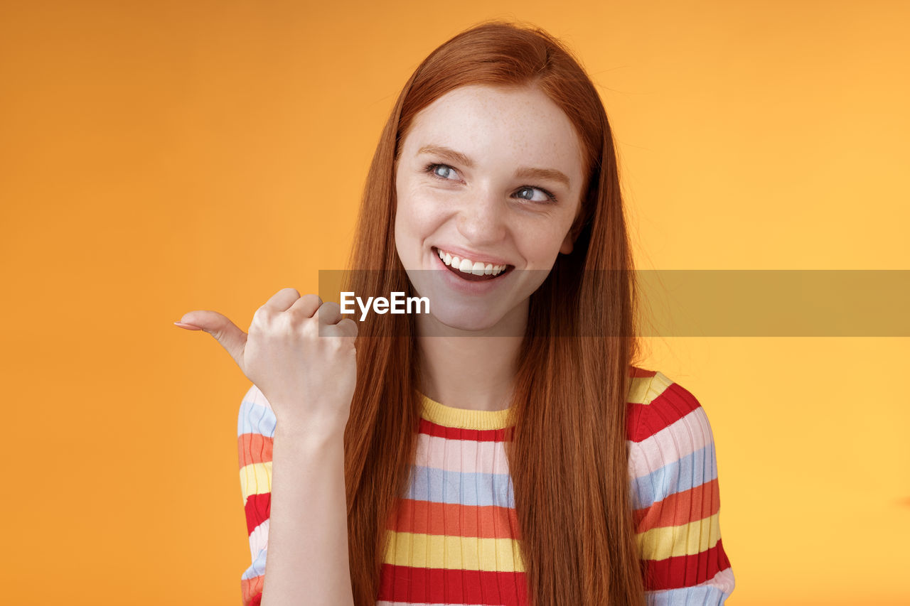 PORTRAIT OF SMILING YOUNG WOMAN AGAINST YELLOW BACKGROUND