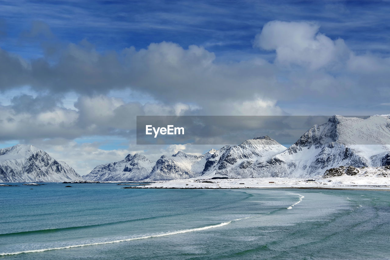 Scenic view of snowcapped mountains at beach against cloudy sky