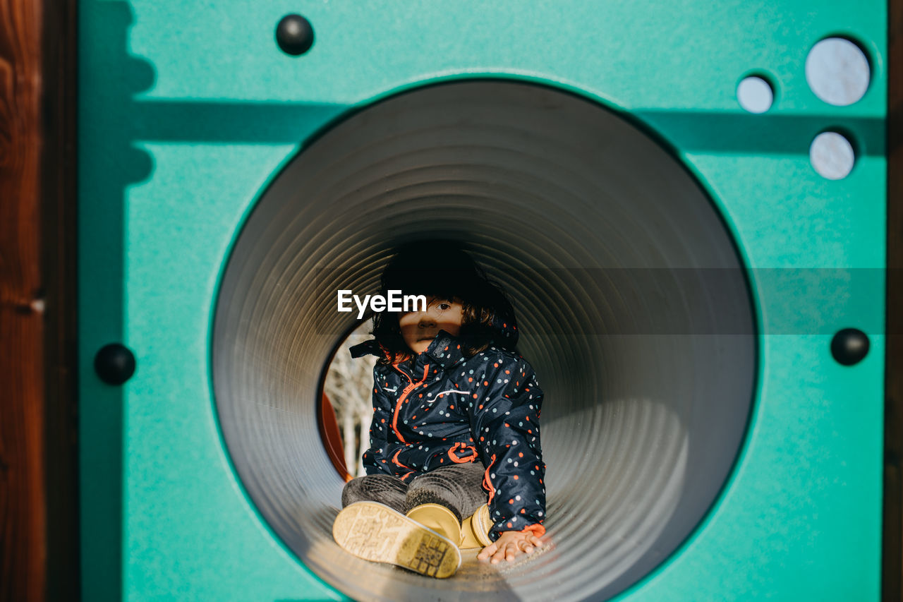 Portrait of cute girl sitting in playing tunnel