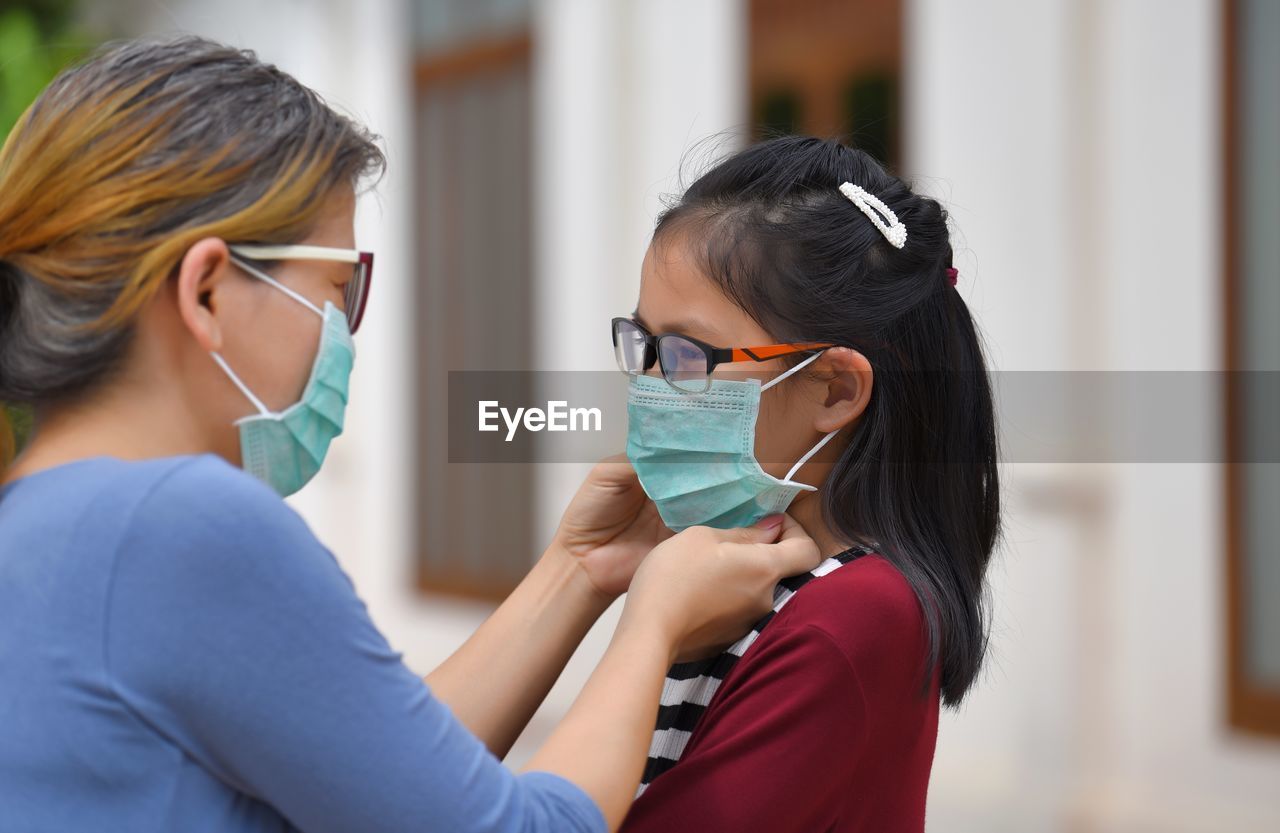 Mother wearing flu mask to daughter outdoors