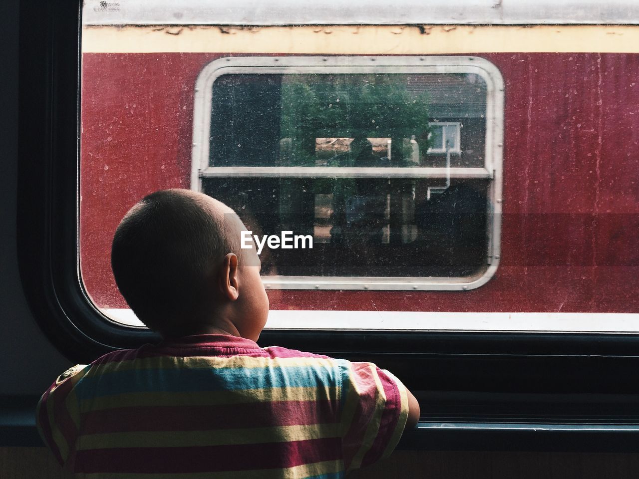 Rear view of boy looking out of window in train