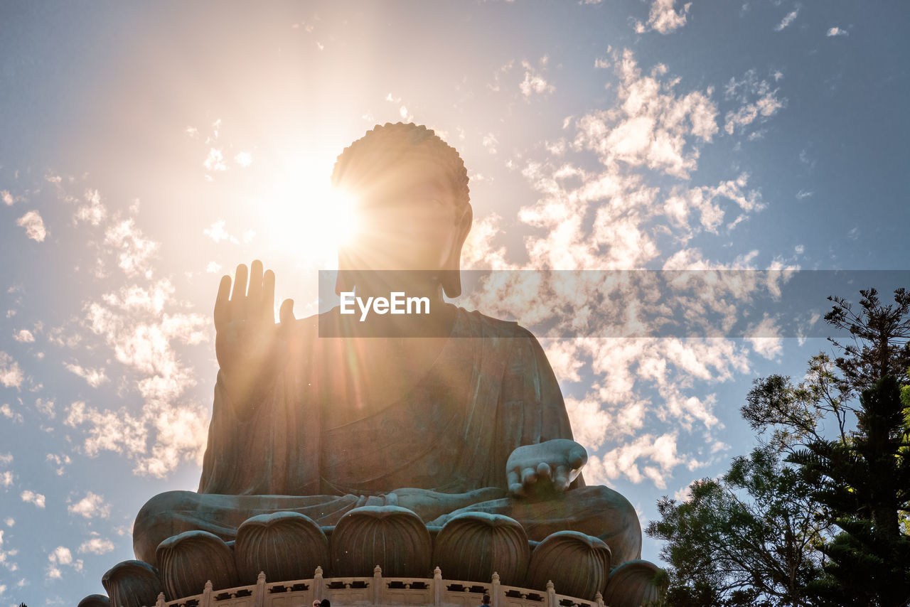 Low angle view of buddha statue against sky