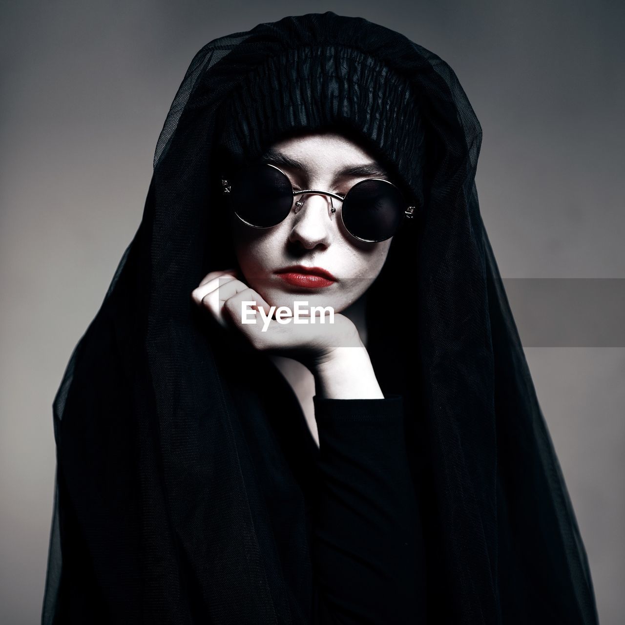 Portrait of beautiful woman wearing sunglasses against gray background