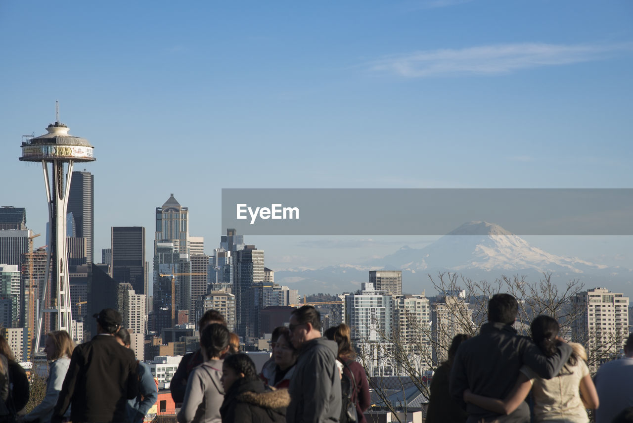 People by space needle in city against sky