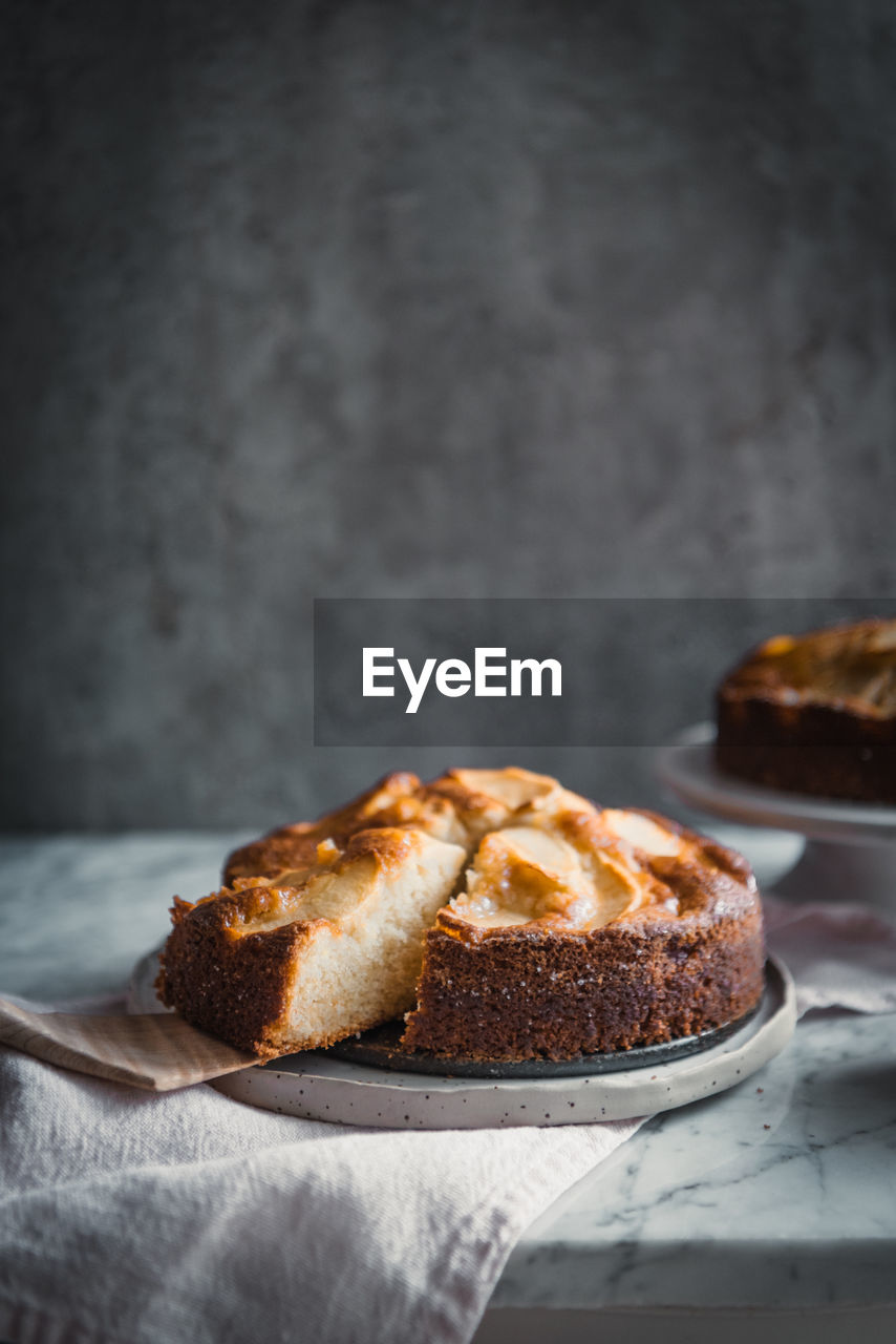 Composition of delectable homemade apple cakes on plates placed on table with bowl with sweet syrup and cooking brush