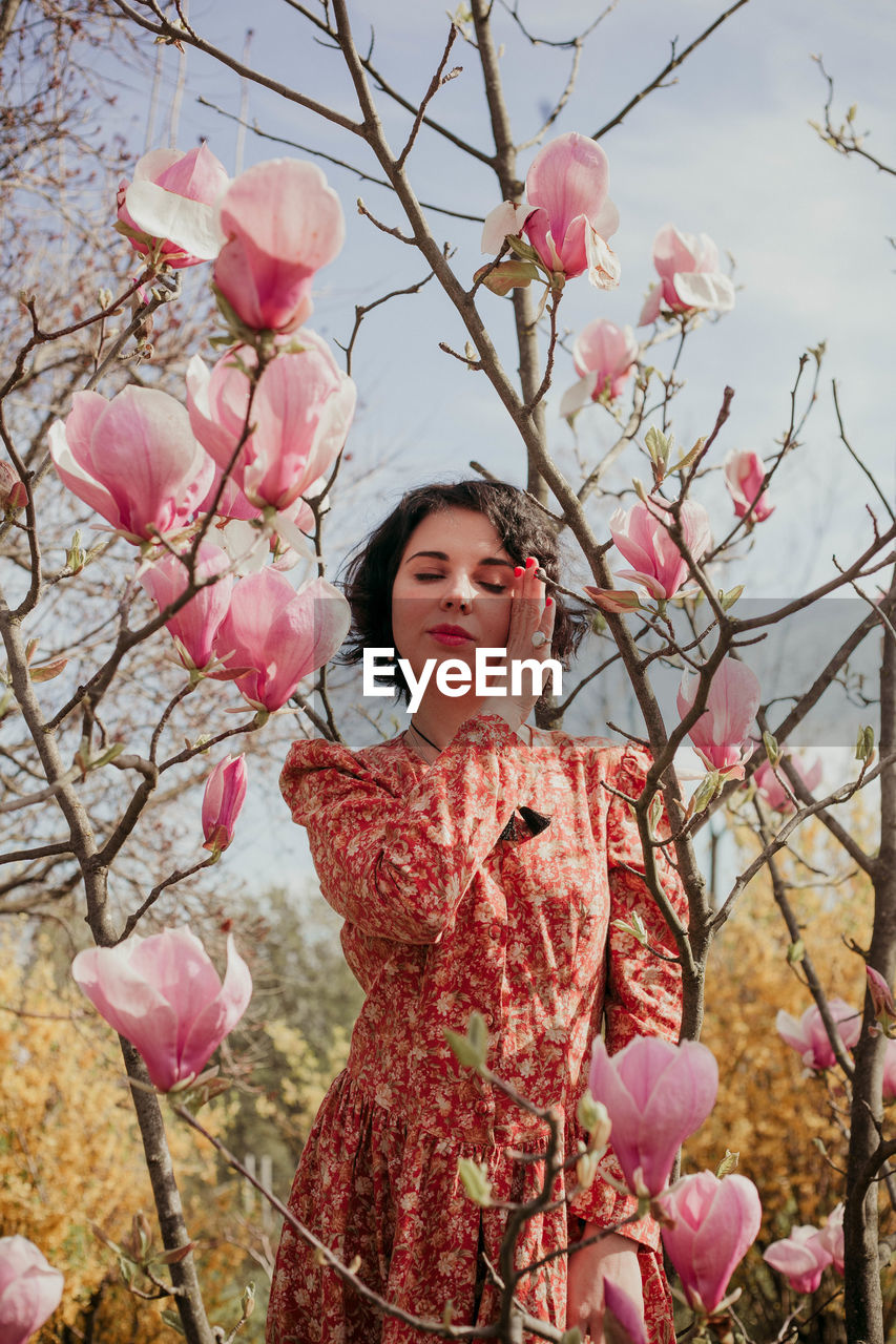 LOW ANGLE VIEW OF WOMAN WITH PINK CHERRY BLOSSOM