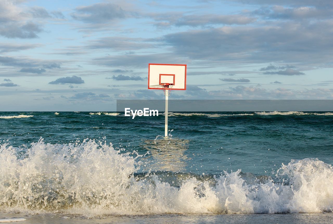 Basketball hoop in sea against sky