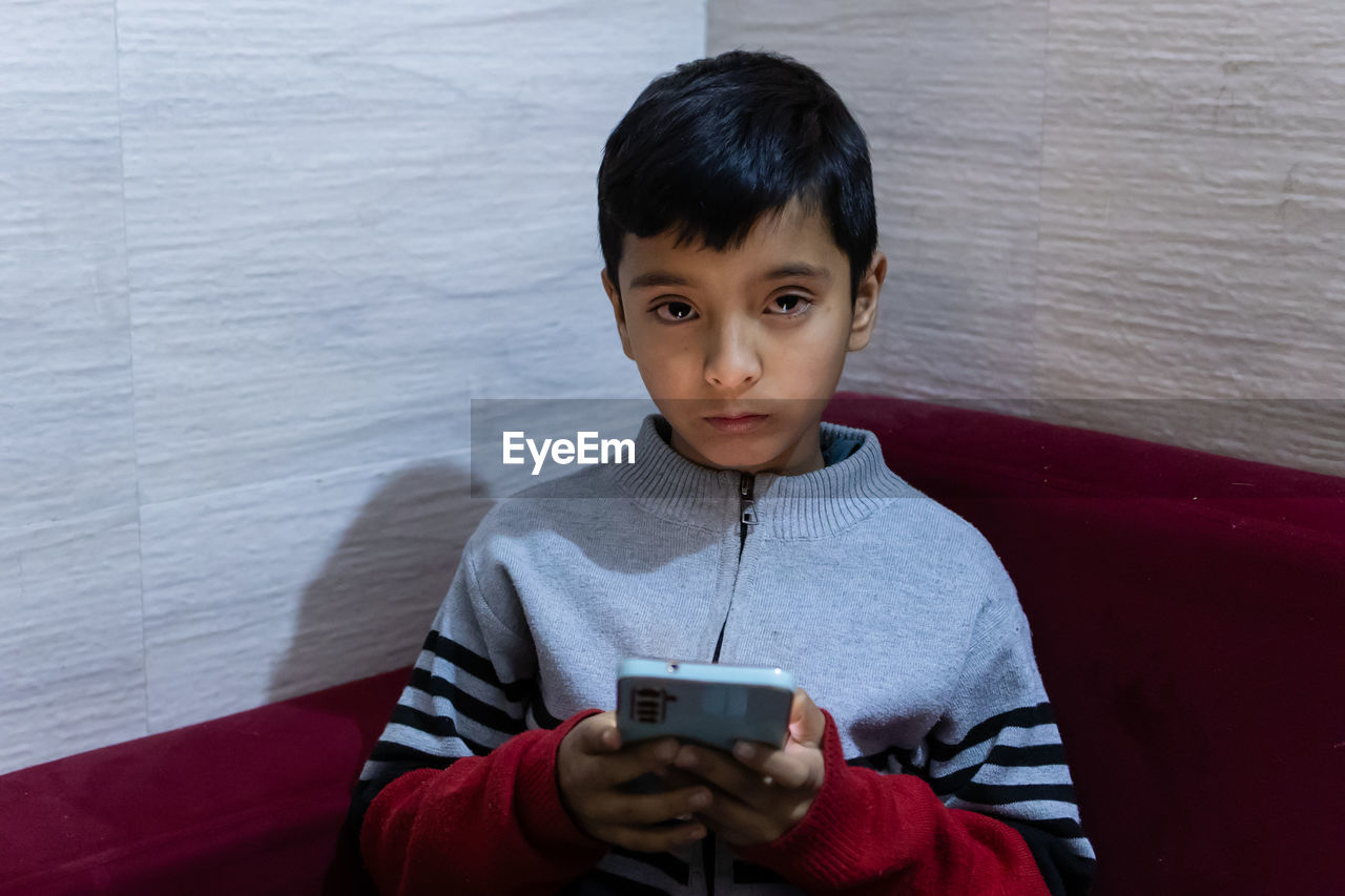 Young kid watching mobile and playing online game at home at night from different perspective