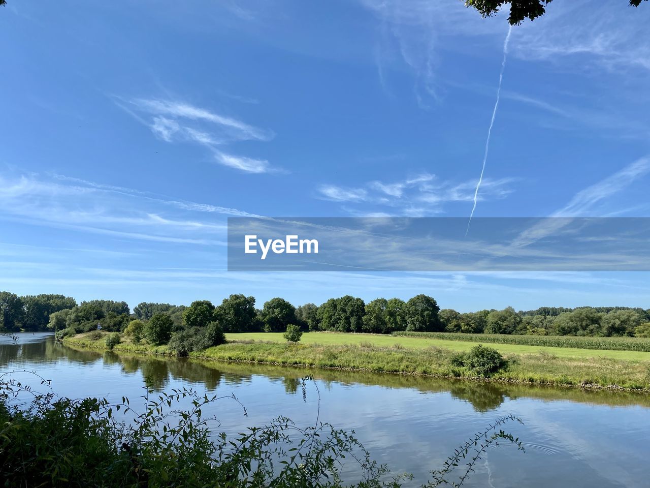 REFLECTION OF TREES IN LAKE AGAINST SKY