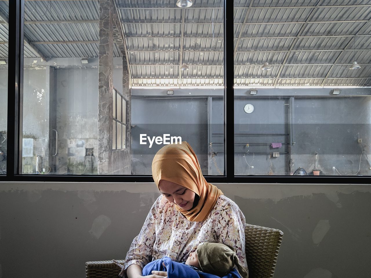 Midsection of woman hokding a baby sitting in glass window