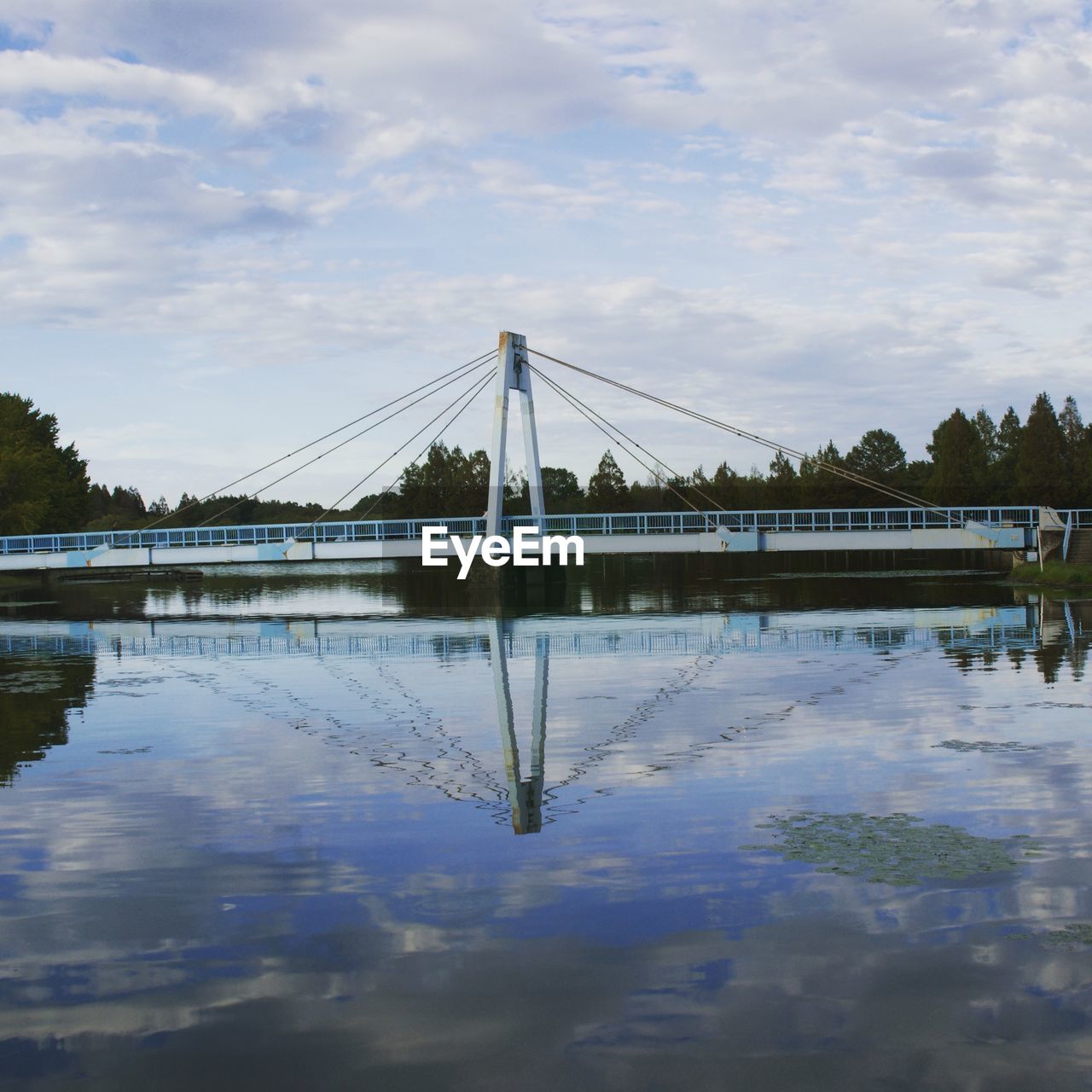 REFLECTION OF BRIDGE ON WATER AGAINST SKY