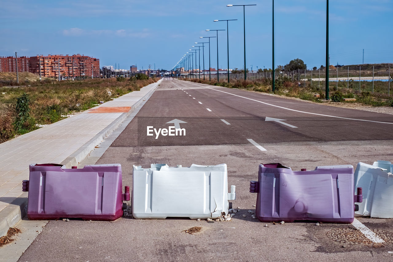 EMPTY ROAD BY CITY AGAINST SKY