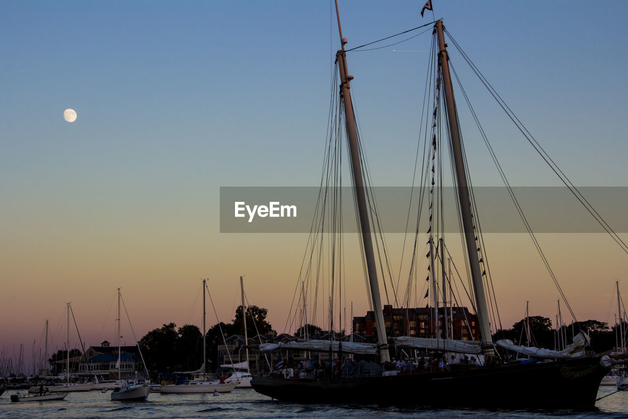 Sailboats moored at harbor