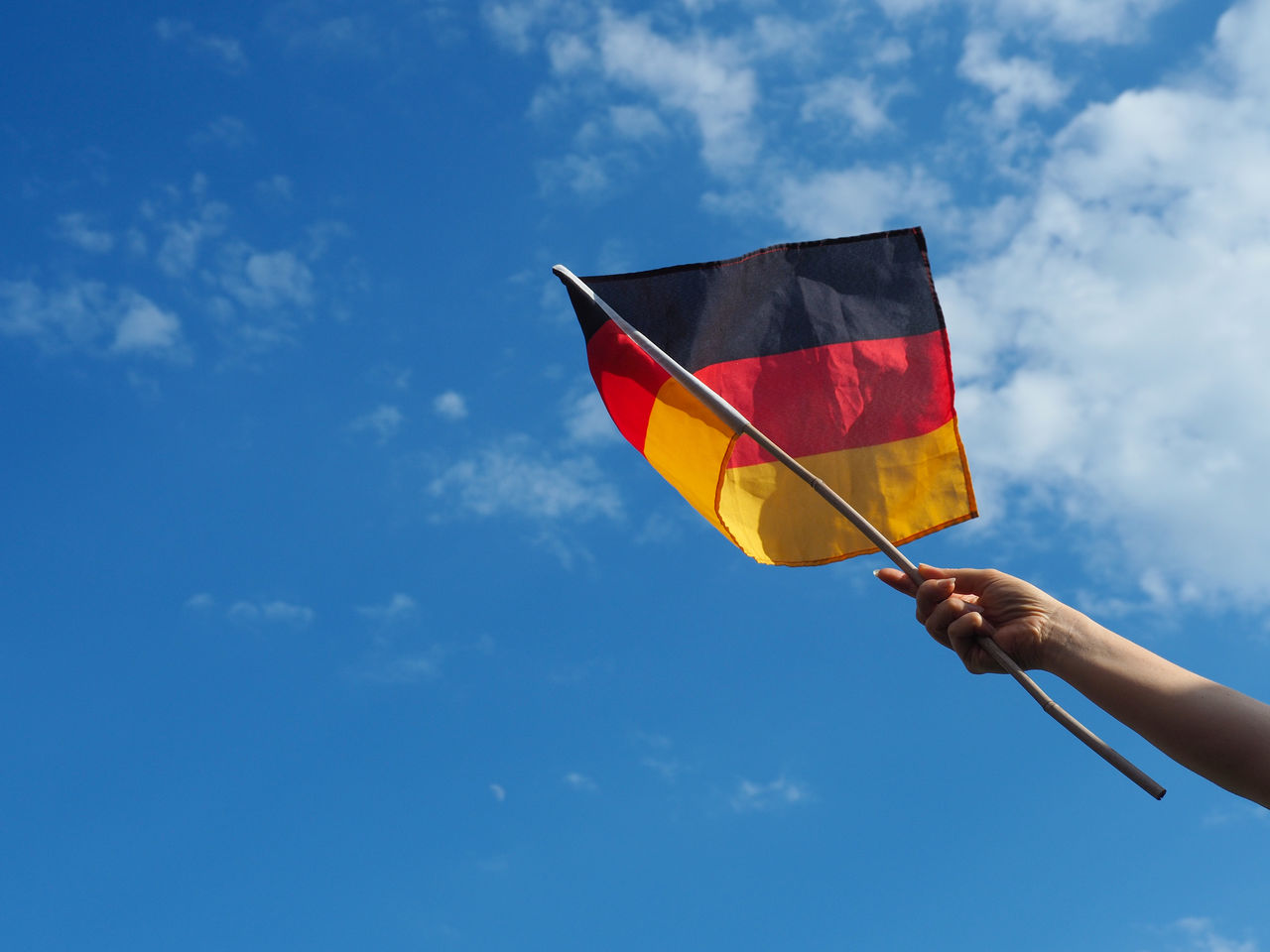 Low angle view of woman holding german flag against sky