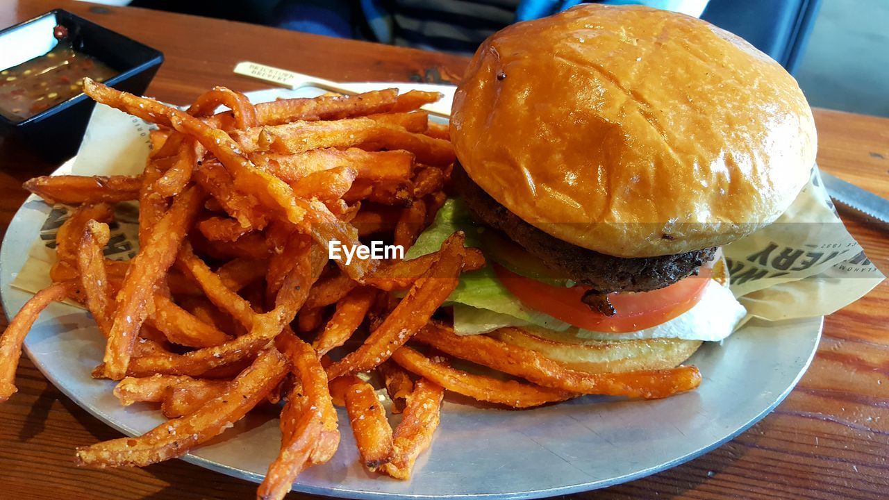 Close-up of burger and french fries in plate on table