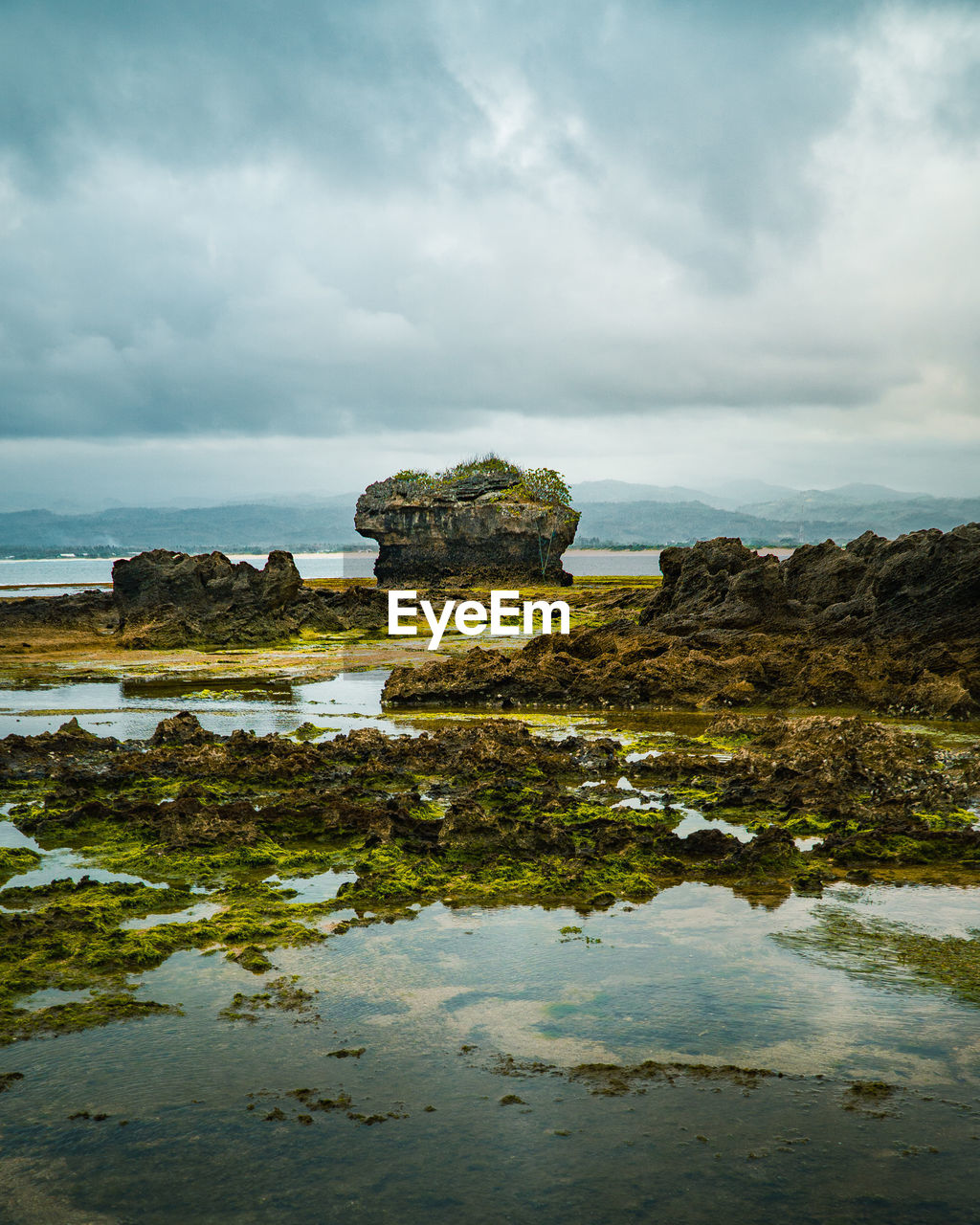 ROCK FORMATION ON SEA AGAINST SKY