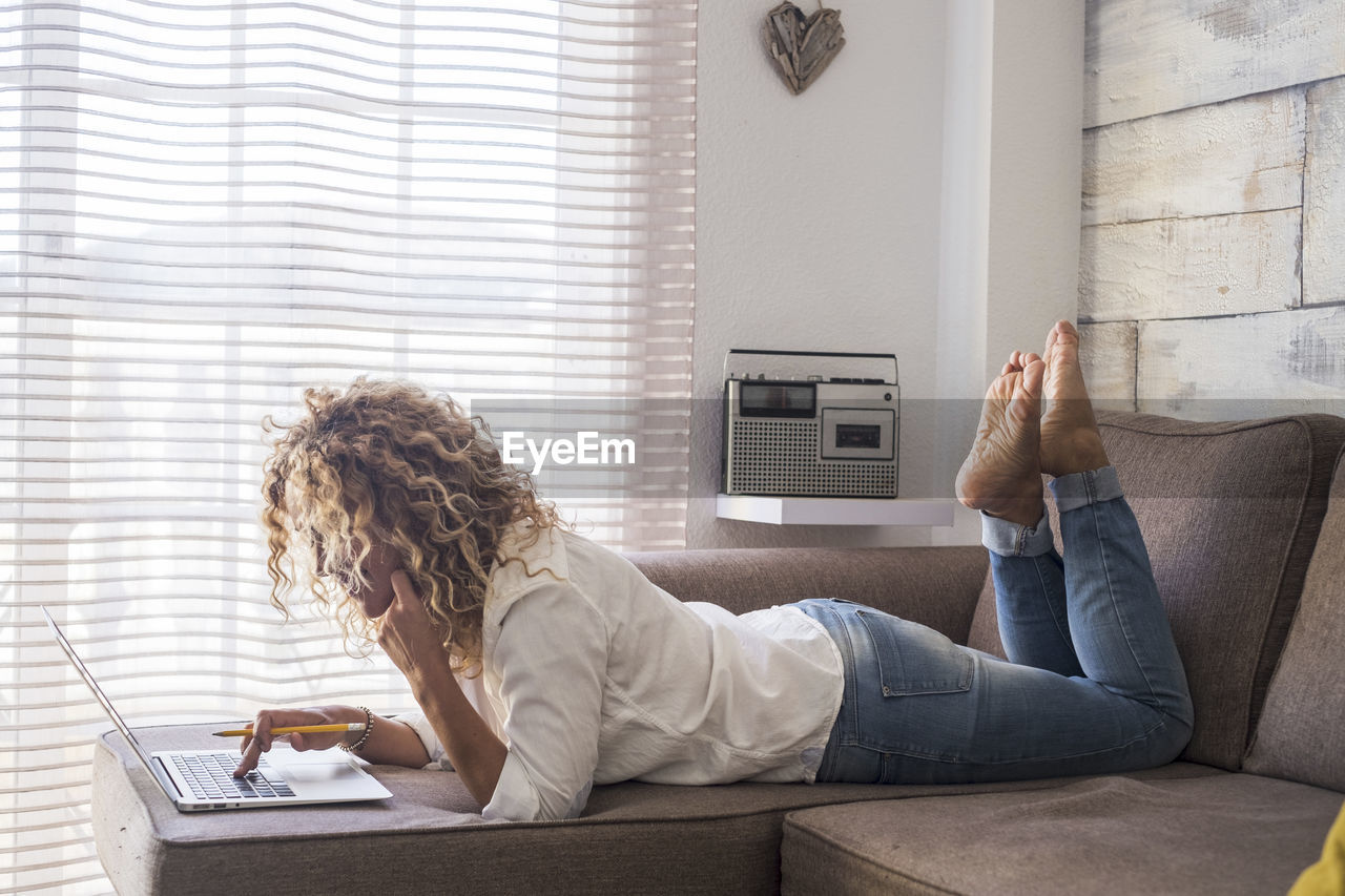 Woman using laptop on sofa at home