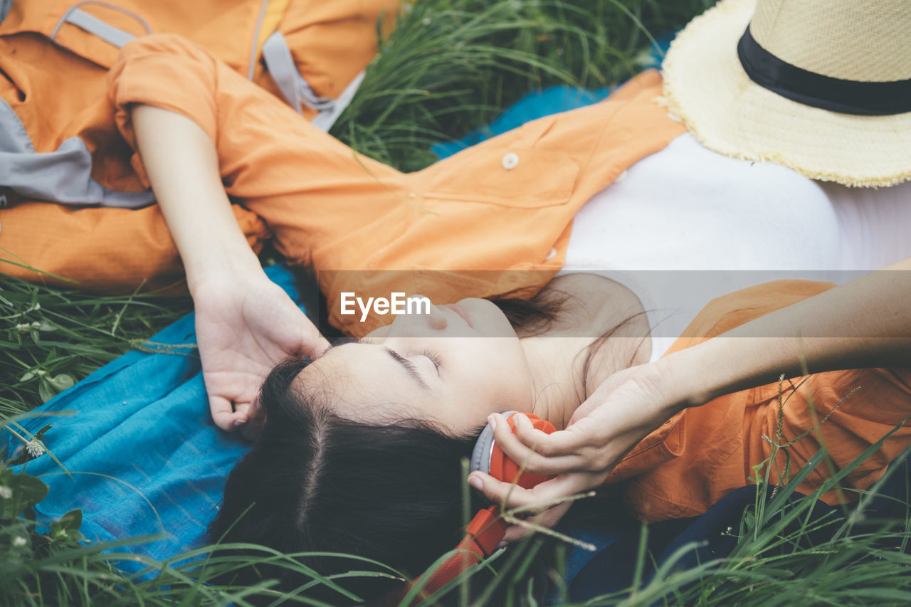 High angle view of woman listening music while lying on grass