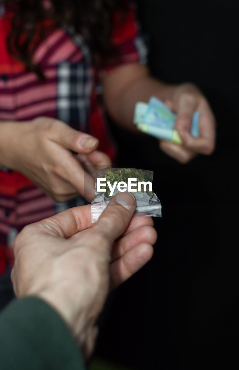 Close-up of man giving marijuana to woman