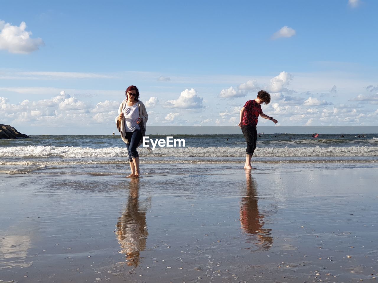 Full length of woman standing with son at beach