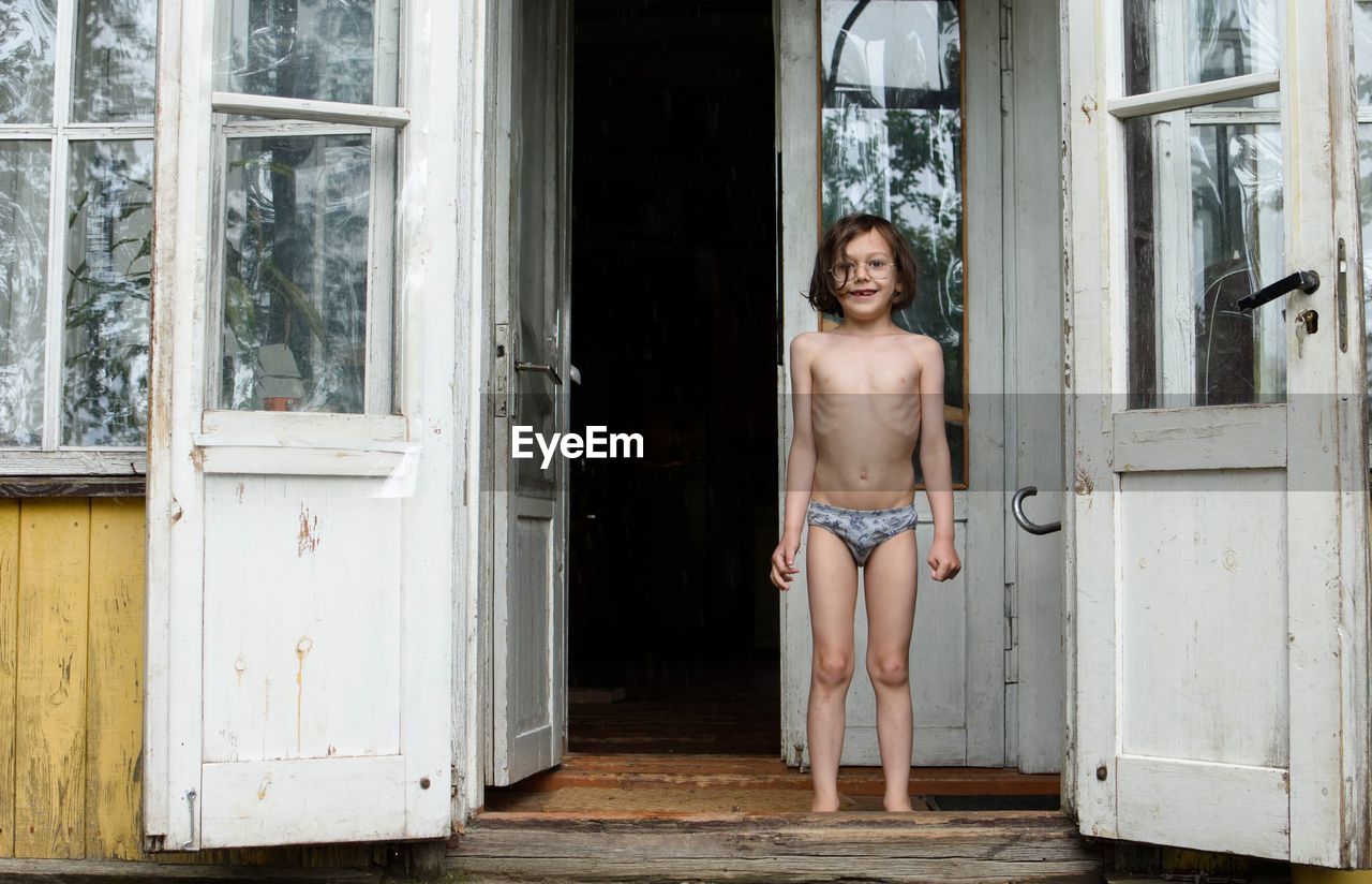 Portrait of shirtless boy standing at doorway