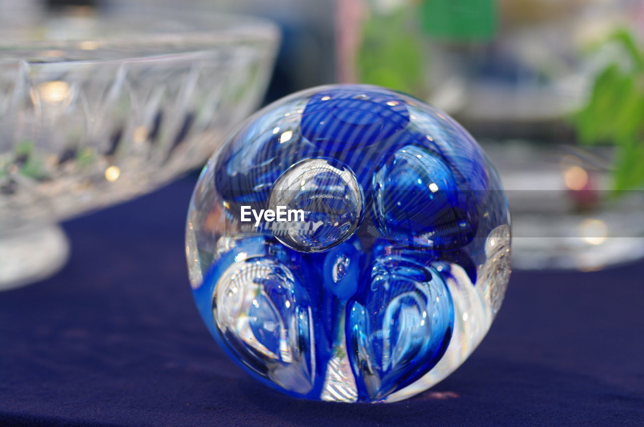 CLOSE-UP OF BLUE CRYSTAL BALL ON WHITE TABLE