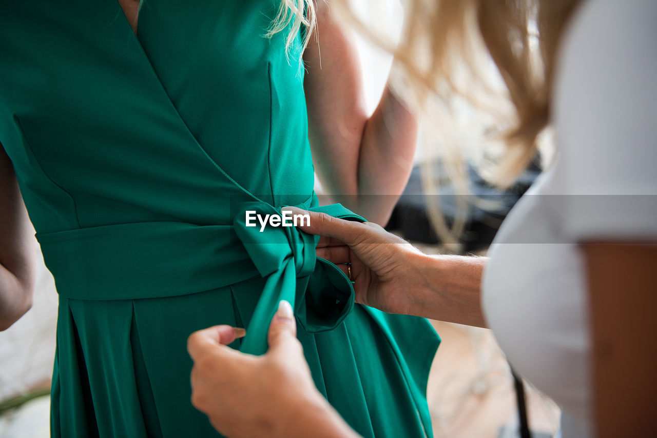 Midsection of woman helping friend to get dress