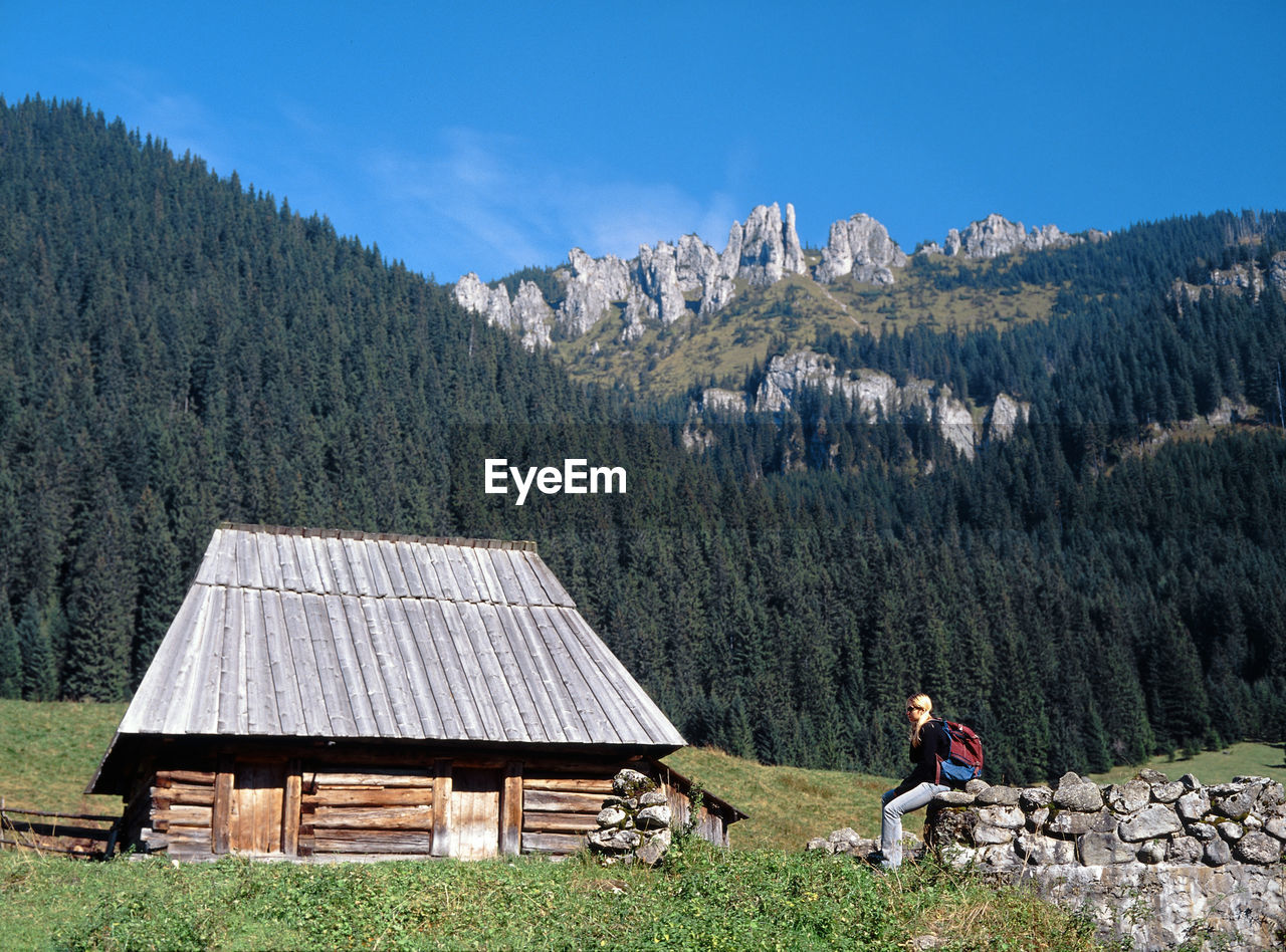 MAN STANDING BY MOUNTAIN AGAINST SKY