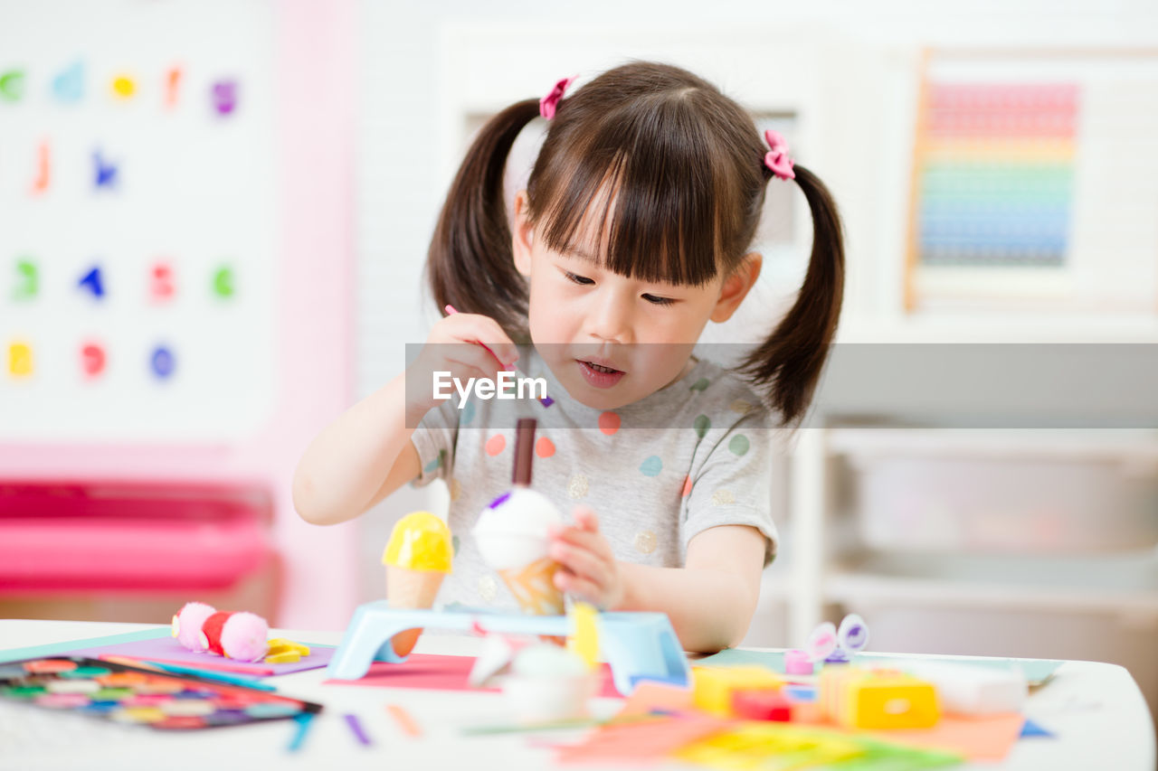 Young girl decorating hand made craft for homeschooling