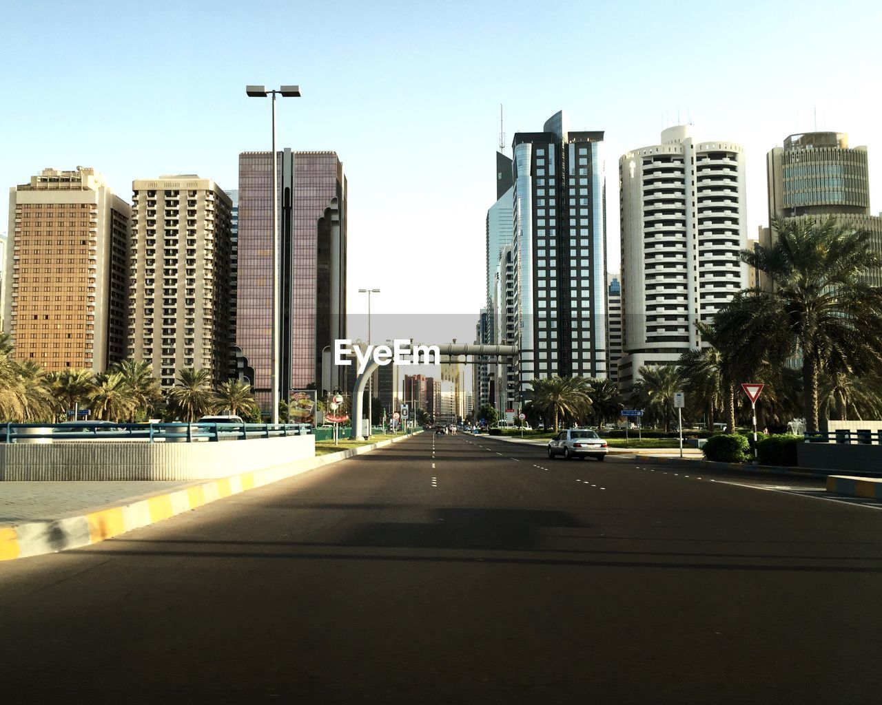 City street by modern buildings in city against clear sky