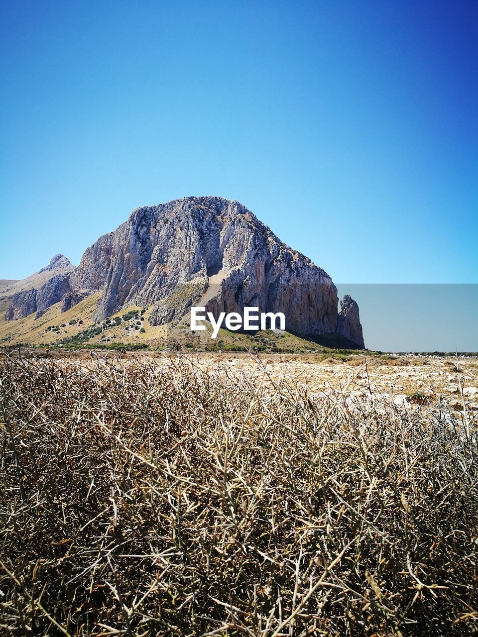 SCENIC VIEW OF FIELD BY MOUNTAIN AGAINST CLEAR BLUE SKY