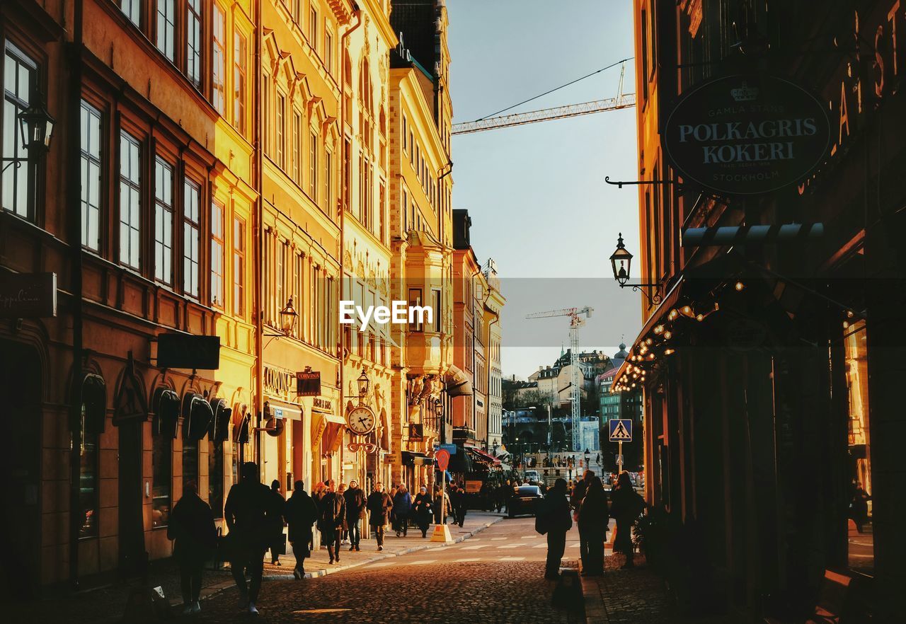 PEOPLE WALKING ON CITY STREET AMIDST BUILDINGS