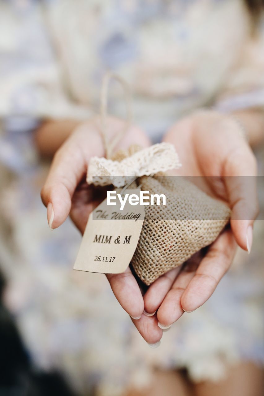Midsection of hand holding small jute sack with text