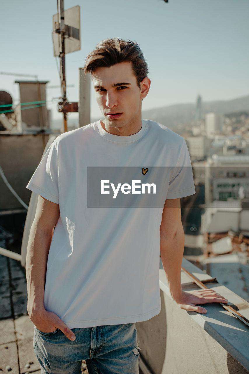 YOUNG MAN STANDING AGAINST CITY