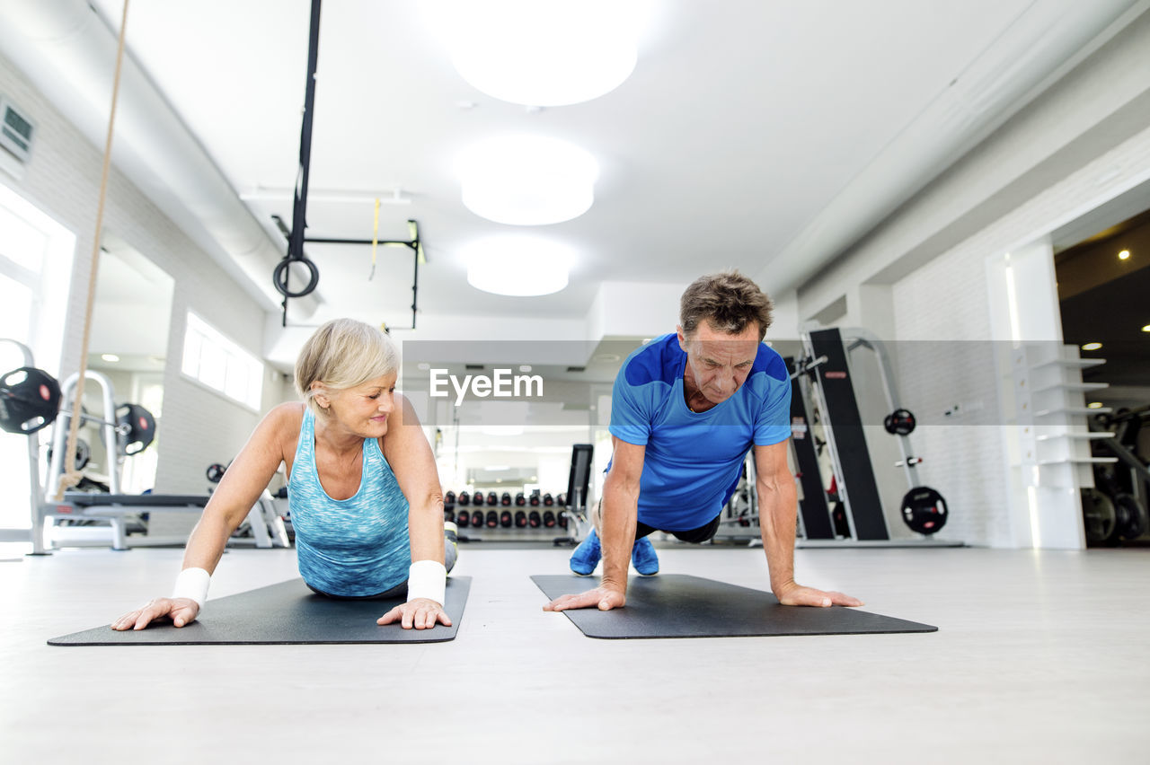 Senior man and mature woman exercising in fitness gym