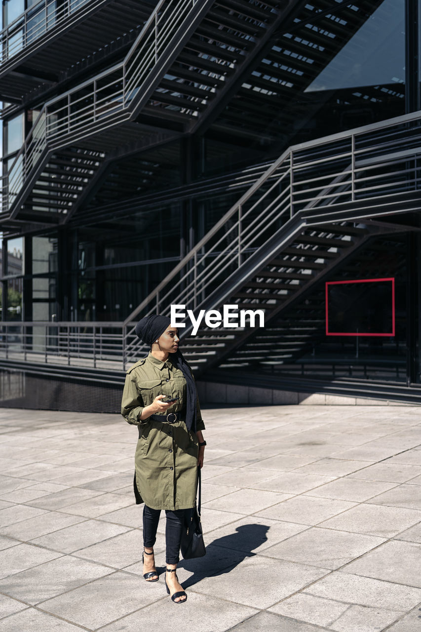 Portrait of modern muslim woman outdoors using her smartphone