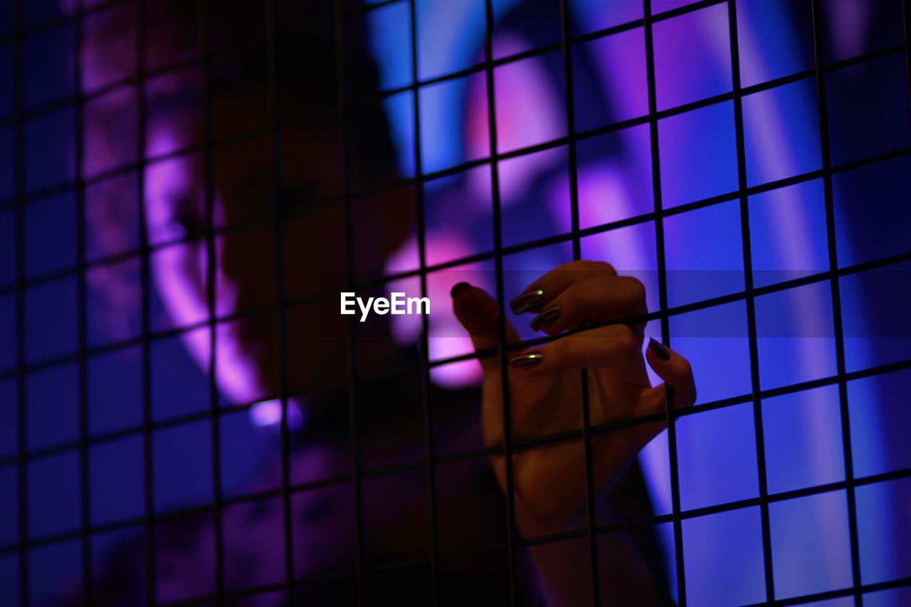 Portrait of woman against chainlink fence