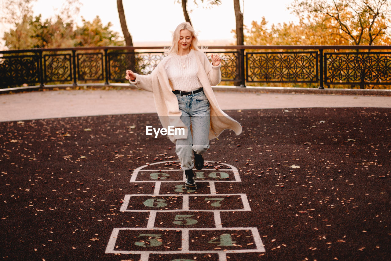 Young woman playing hopscotch in park during autumn