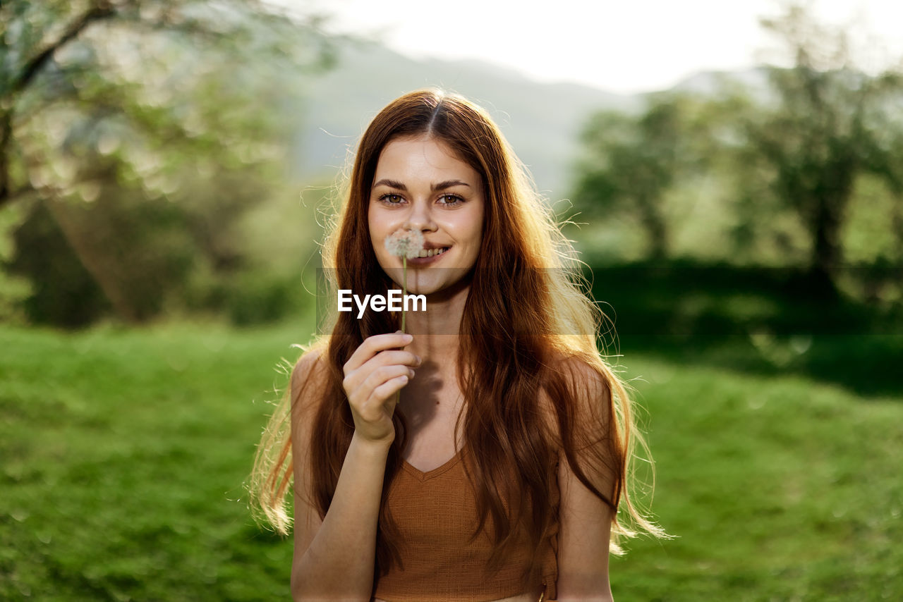 portrait of smiling young woman standing on field