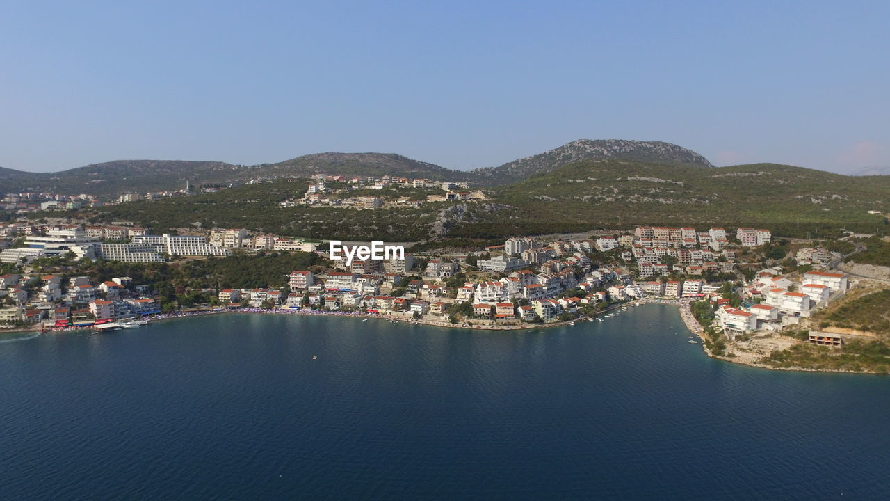 Aerial view of townscape by sea against clear sky