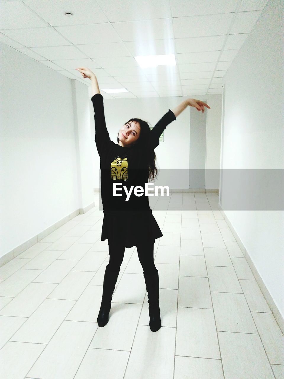 Portrait of happy teenage girl posing in illuminated white university corridor