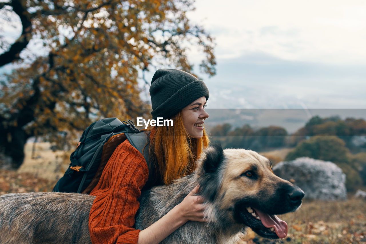 PORTRAIT OF YOUNG WOMAN WITH DOG ON TREE