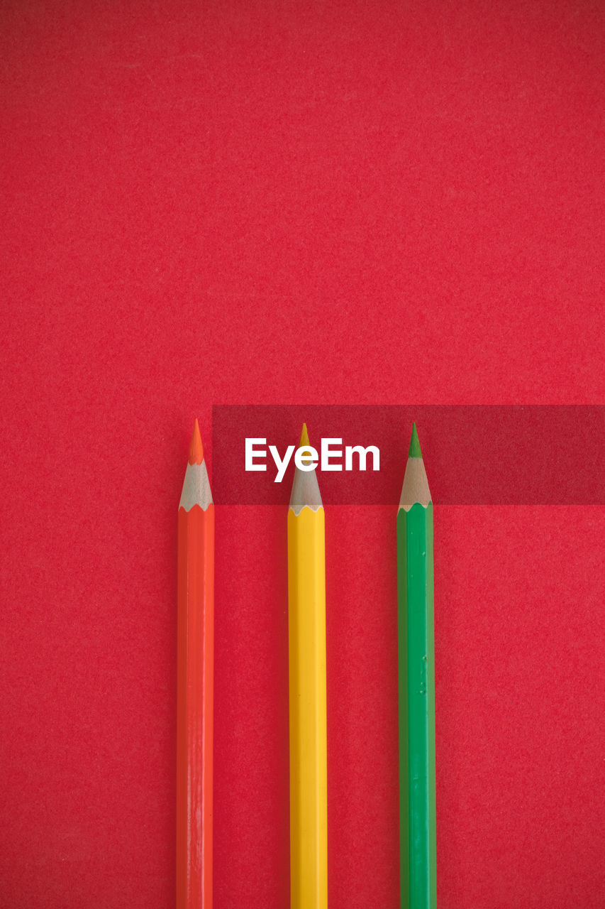 Close-up of multi colored pencils against red background