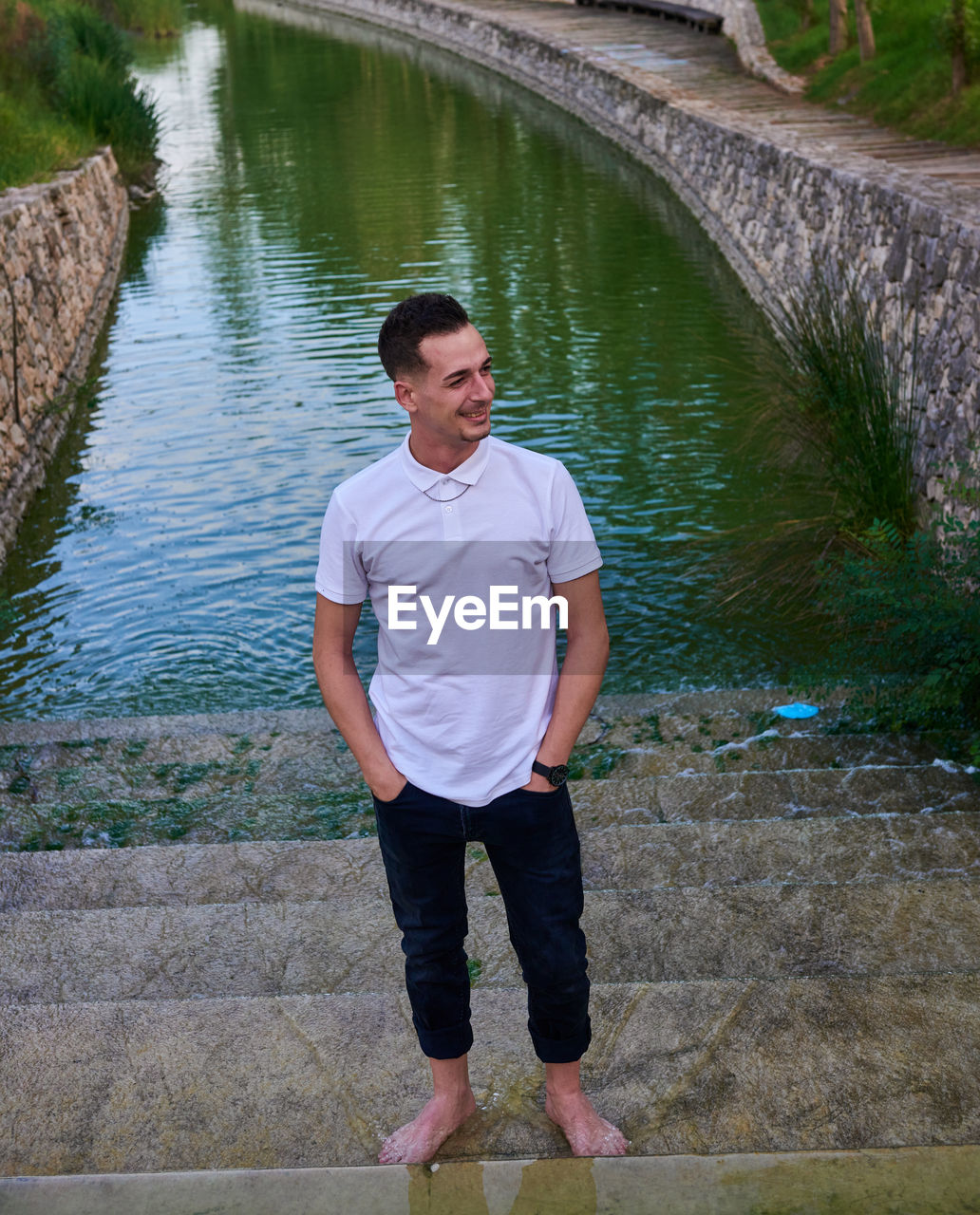 A young man in a white t-shirt inside a pond.