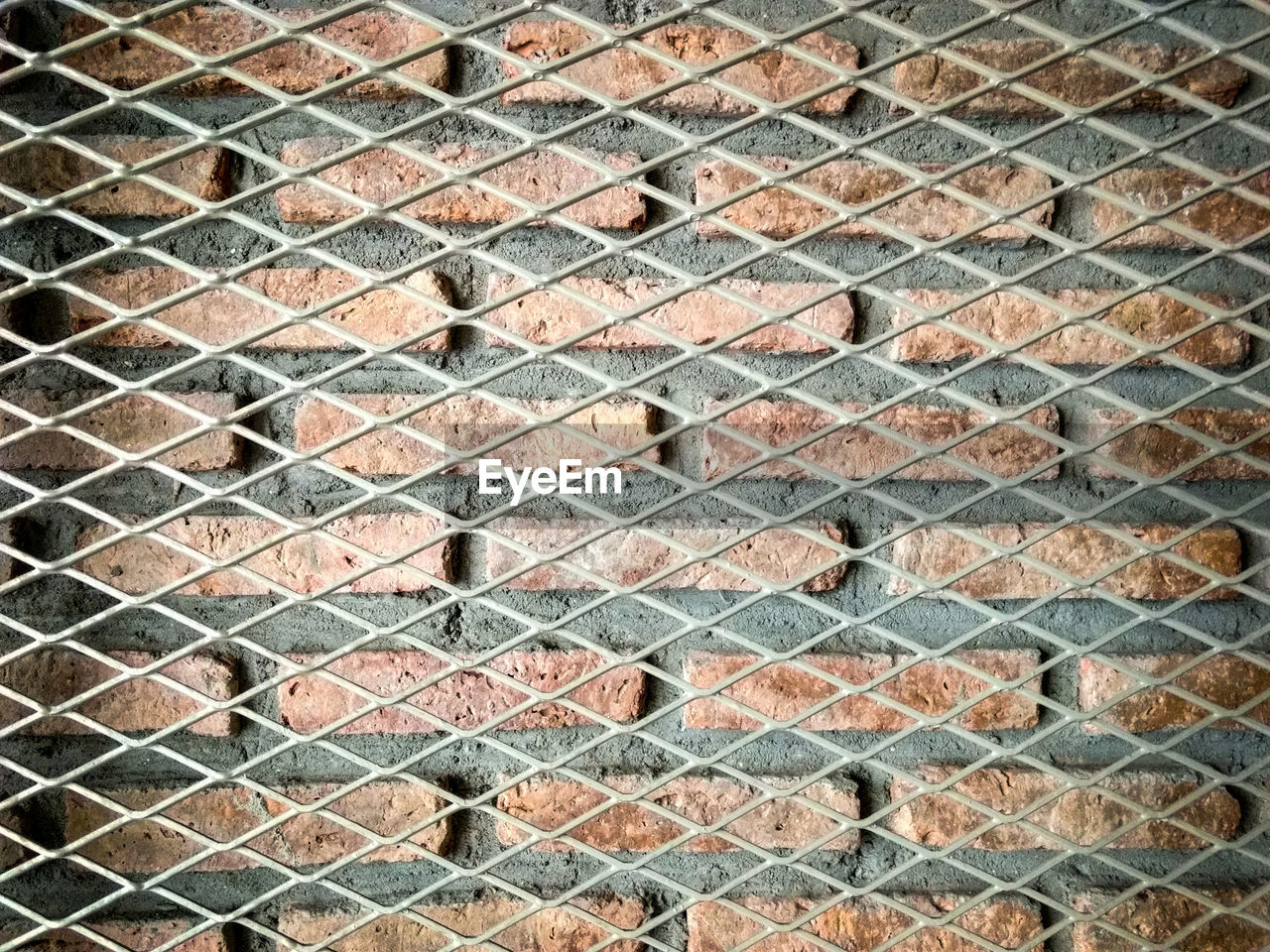 Full frame shot of metal grate against brick wall