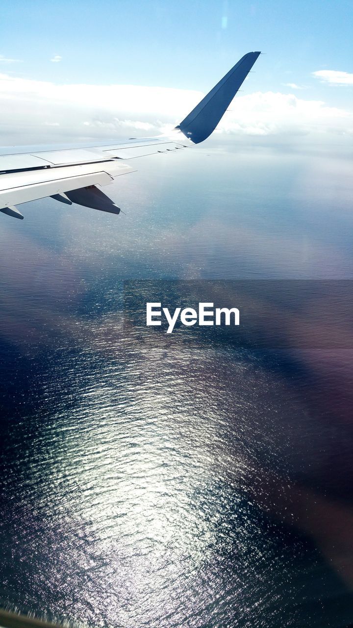 CROPPED IMAGE OF AIRPLANE FLYING OVER SEA