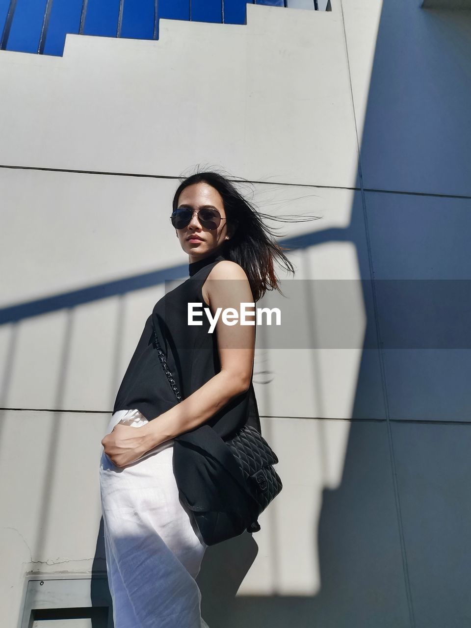 Portrait of young woman wearing sunglasses against sky