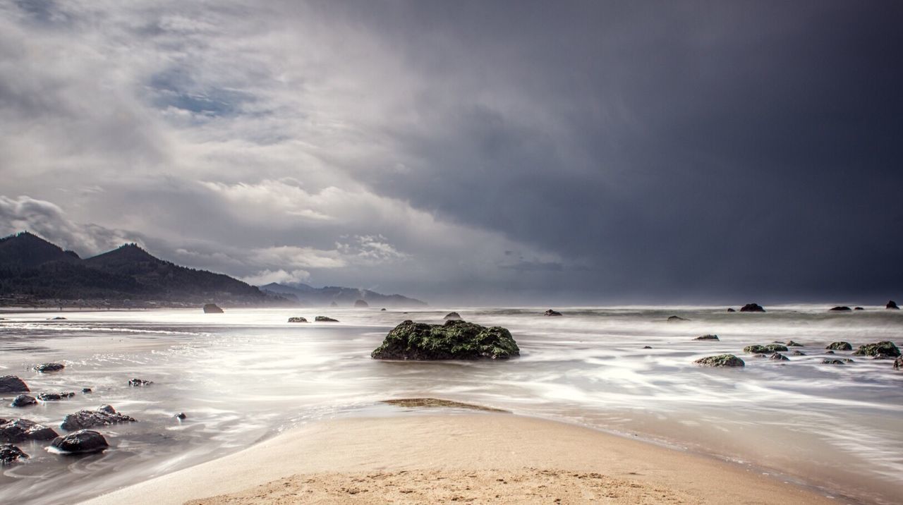 Scenic view of beach against cloudy sky