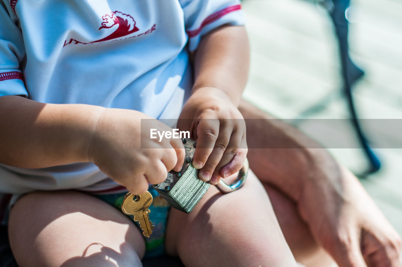 Midsection of kid playing with padlock and key