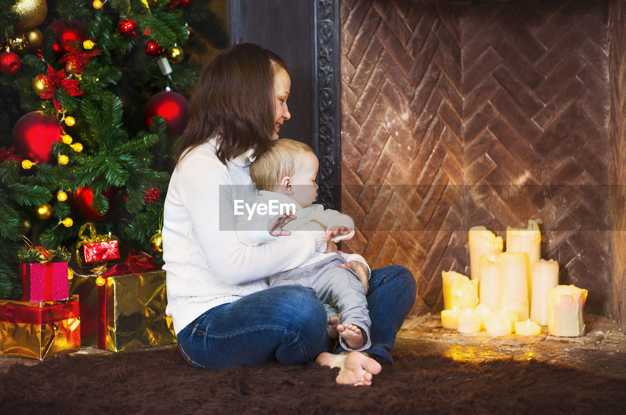 REAR VIEW OF WOMAN SITTING IN CHRISTMAS TREE